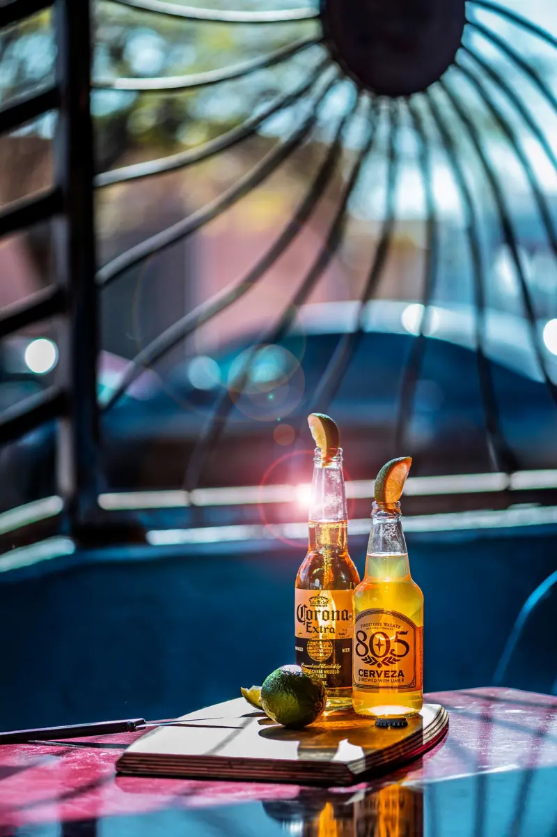 Two Mexican beers with lime on a sunlit restaurant patio table