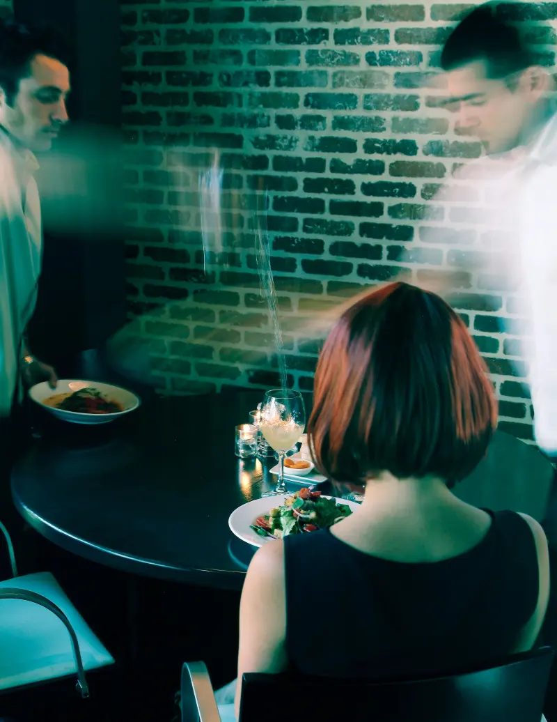 Servers moving past a diner at a candlelit table, capturing restaurant atmosphere