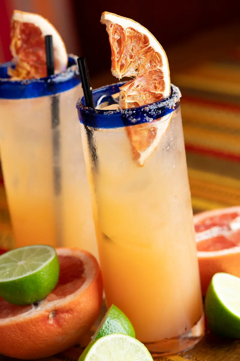 Grapefruit paloma cocktails with blue sugar rims and fresh limes
