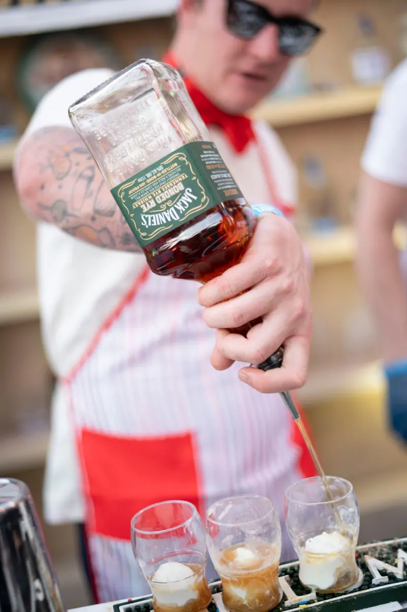 Bartender pouring whiskey shots at a festival bar